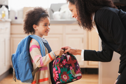 Mixed race mother handing lunch box to daughter